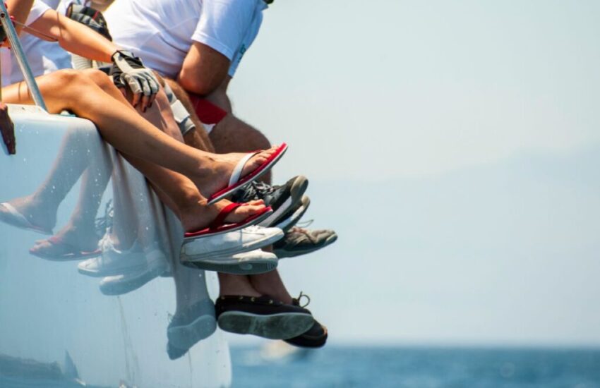 The group of friends are sitting on the side of the yacht.