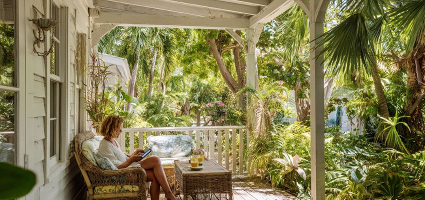 Woman relaxing on a shaded porch with a book at a lush Captiva Island vacation home, Florida