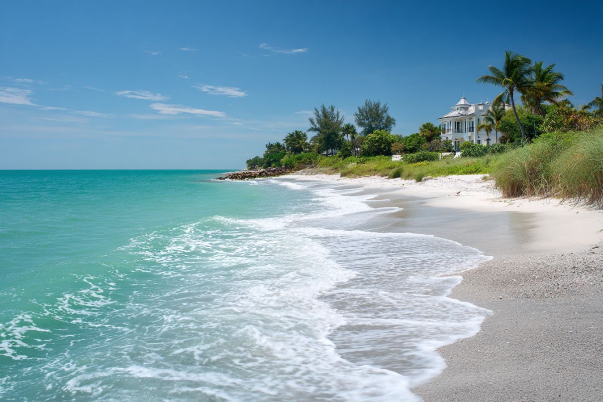 Turquoise waves washing onto the white sand beach with a beautiful home overlooking Captiva Island, Florida
