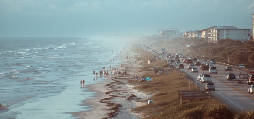 Busy beach day at Cocoa Beach with people on the sand and cars along the coastal road